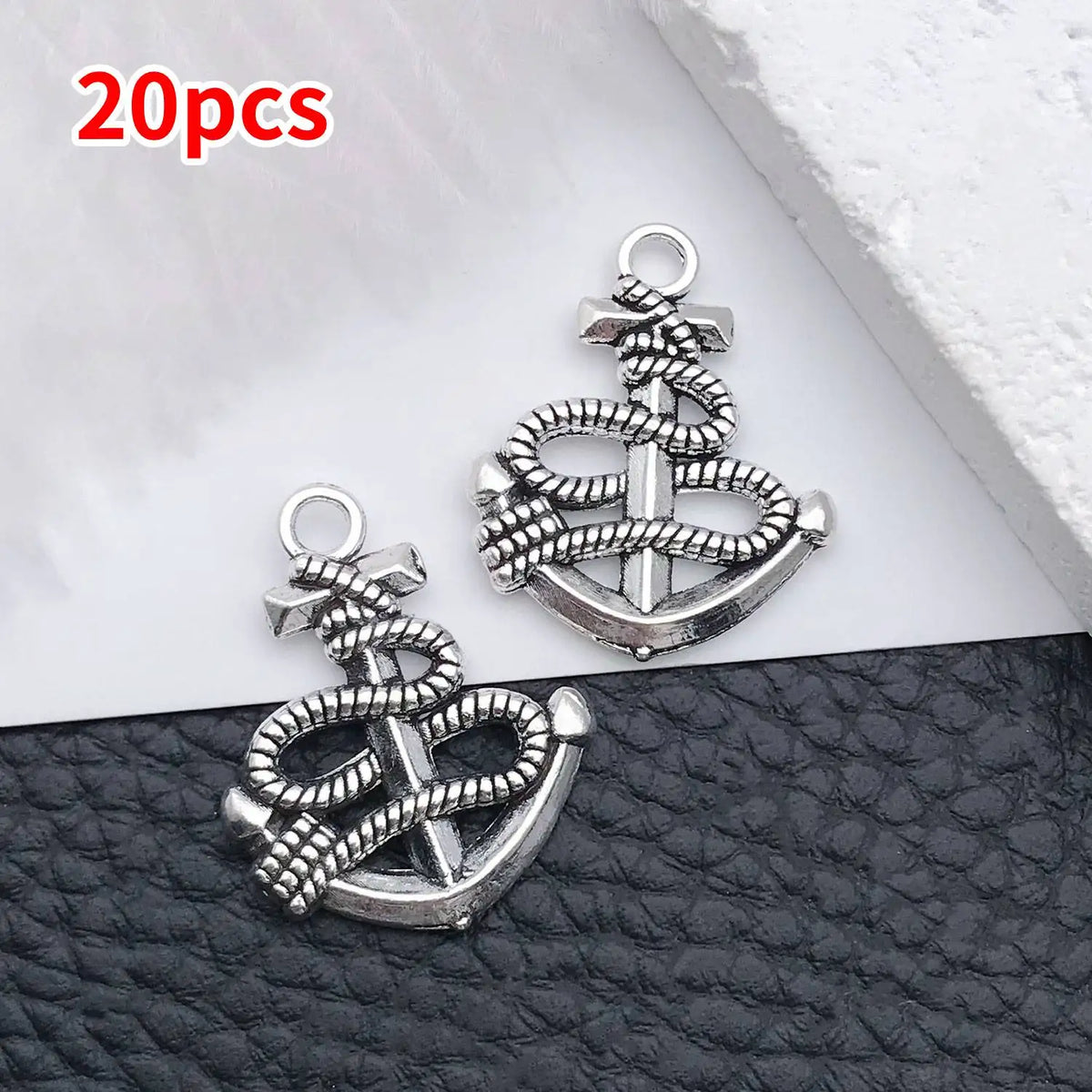 20 pieces of silver vintage ship anchor charms for jewelry making displayed on a dark surface.
