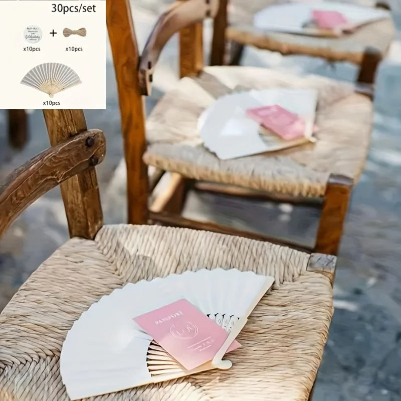 A set of bridal handheld folding fans with pink accents displayed on a woven chair.