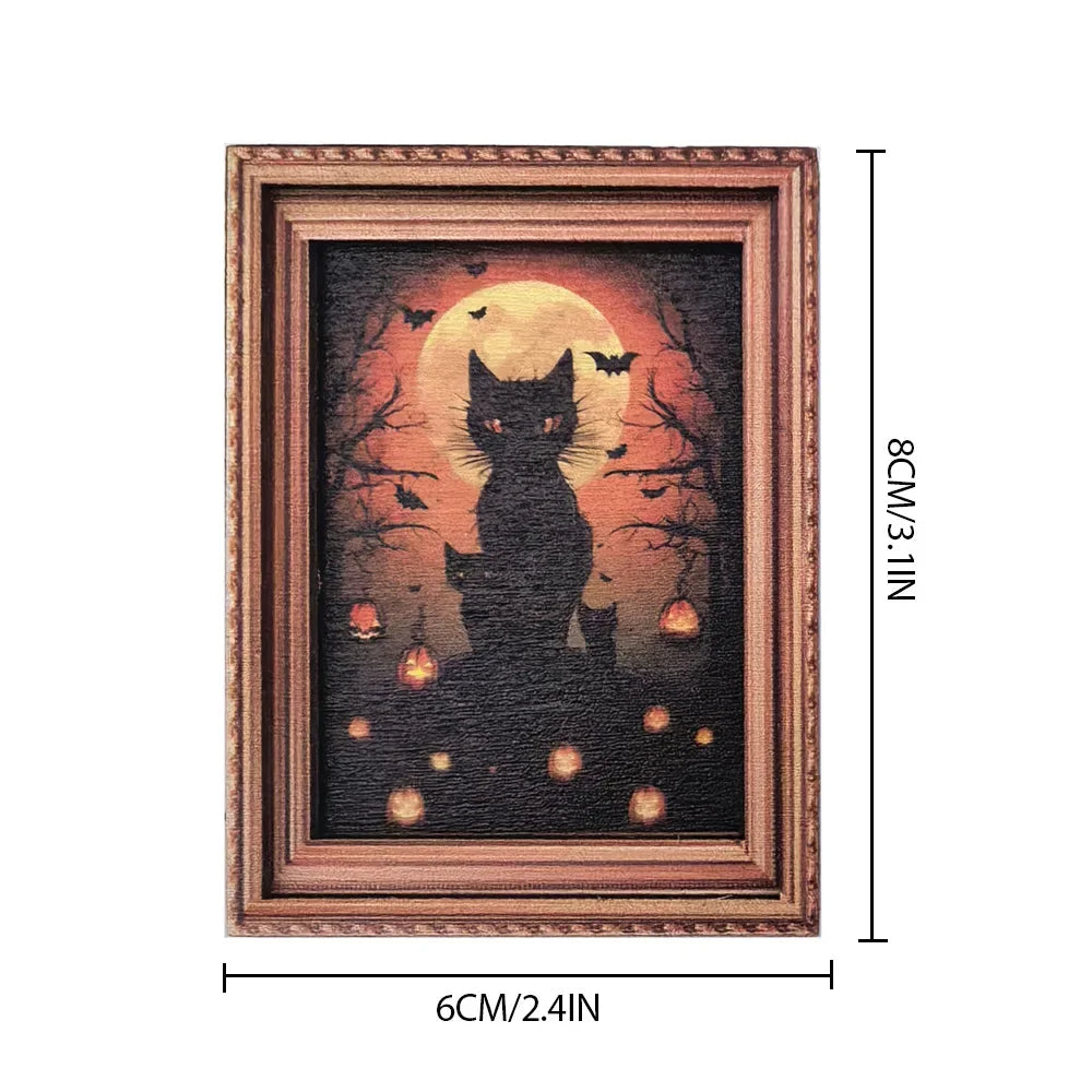 A framed print featuring a silhouette of a black cat against an orange moon and dark trees with small bats and glowing pumpki