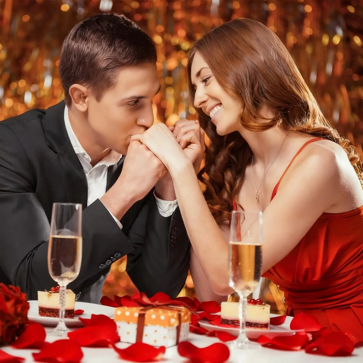 A woman and a man looking at each other while surrounded by red rose petals on a white table.
