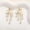 Gold-toned needle earrings featuring a diamond stud and dangling pearl tassels.