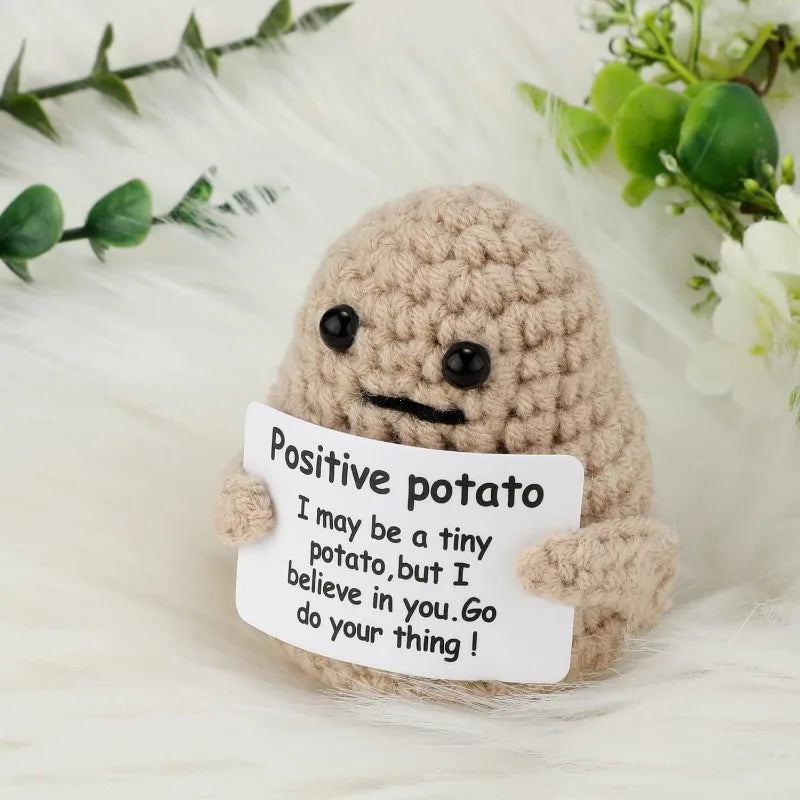 A handmade knitted plush doll resembling a potato with a handwritten note attached.