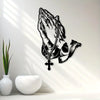 Black metal wall art depicting praying hands with a cross, cast in a silhouette style.