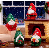 A set of festive resin Christmas dwarf figurines, including a Santa figure, a green Christmas tree, and a red fireplace mante