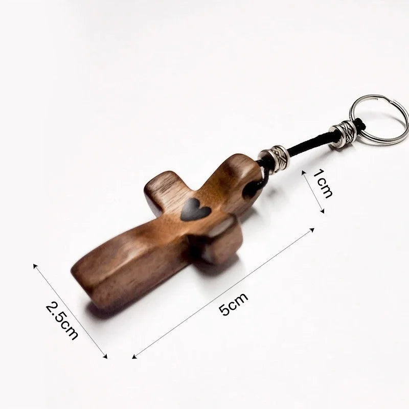 A handcrafted walnut cross keychain with a silver ring and measurement lines.