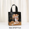 Black non-woven gift tote bag with gold glitter accents and an orange bow design