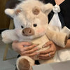 A person is holding a fluffy white Highland cow plush toy in a close-up shot.
