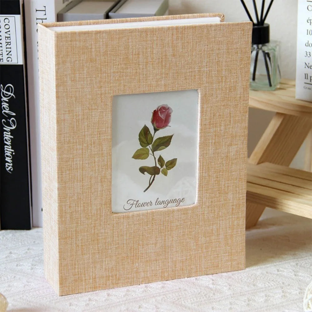 A light wood framed photo album with a linen cover and a floral design inside.