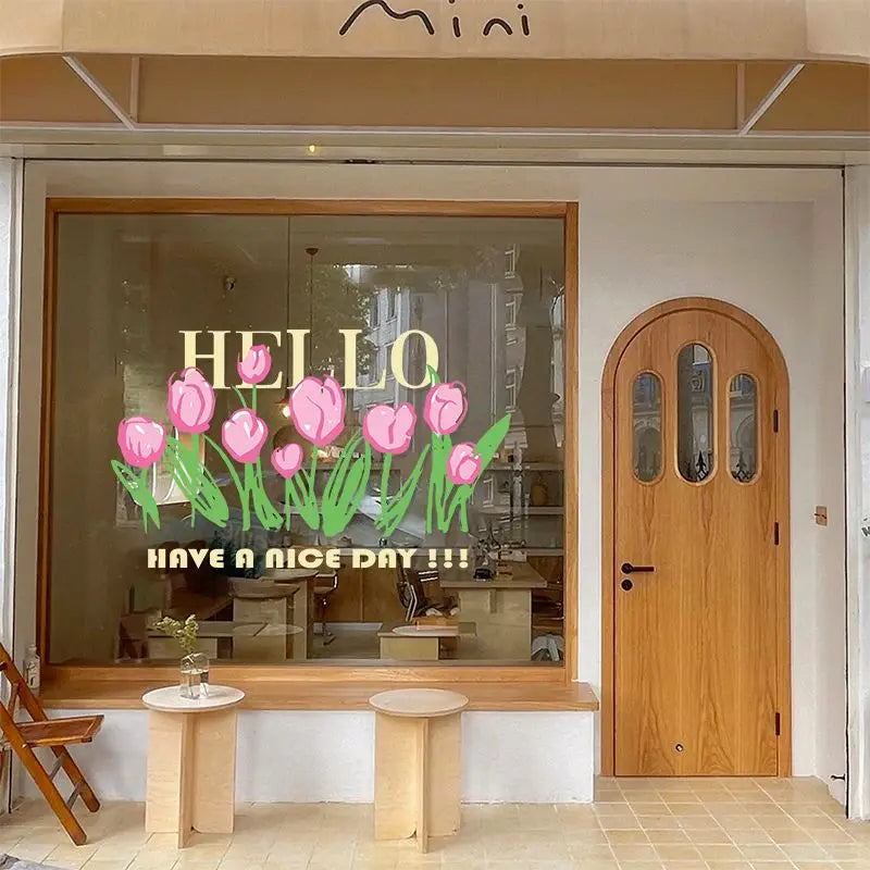 A storefront window displaying pink tulip decals and a wooden door.