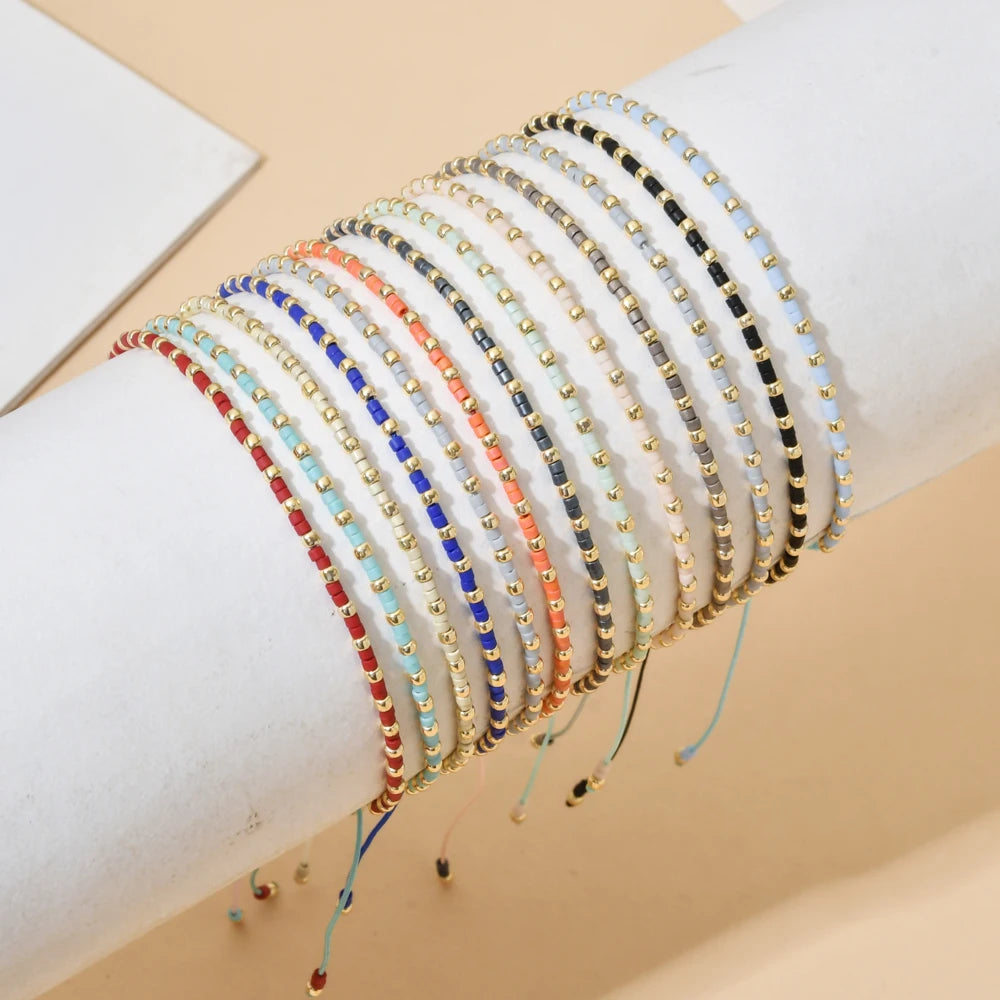 A stack of colorful glass bead bracelets on a wrist, featuring various shades of blue, gold, and red.