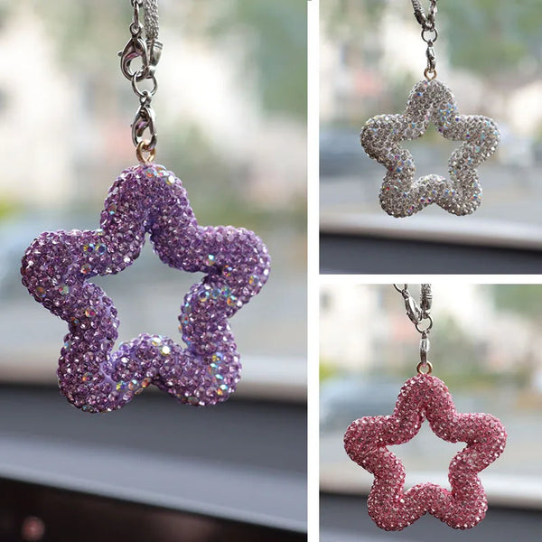 A close-up of a purple rhinestone star charm with crystal accents hanging from a silver chain.