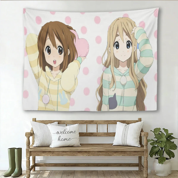 A tapestry featuring two cute anime girls with brown and blonde hair in pastel colors against a pink polka dot background.