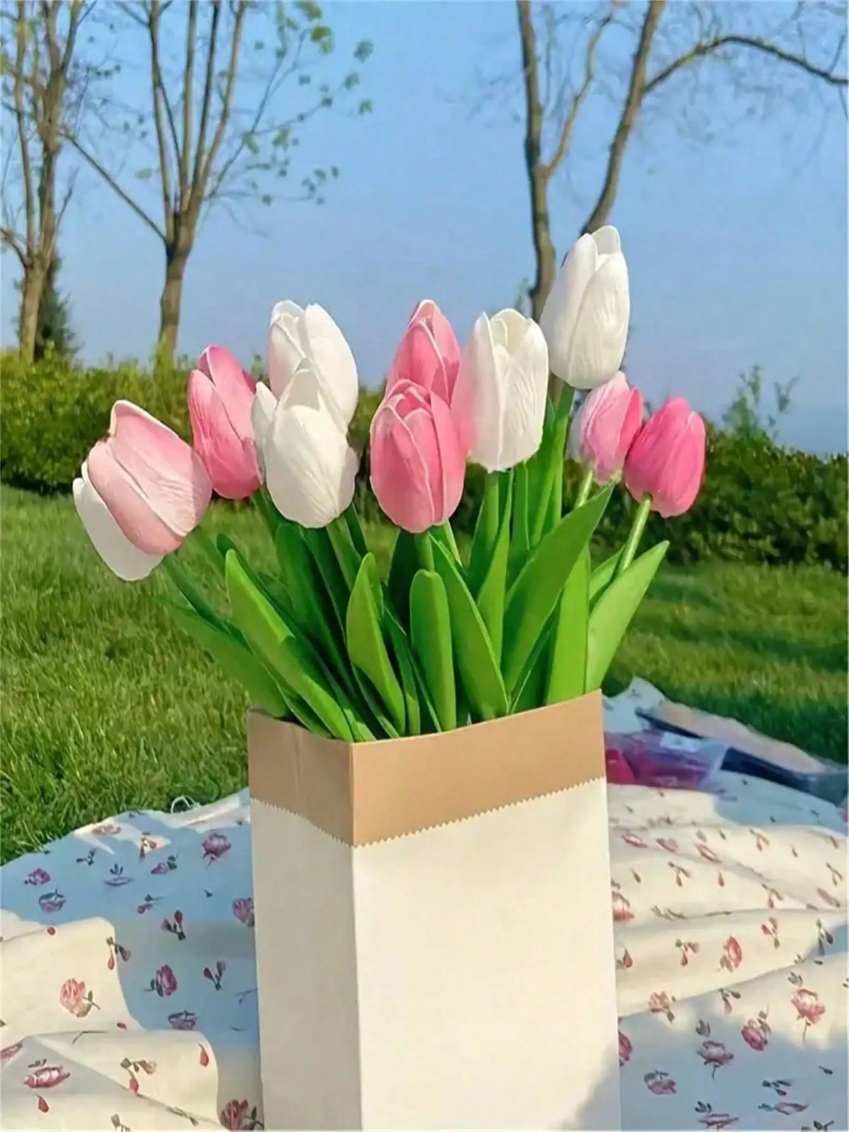 A bouquet of six lifelike artificial tulips in shades of pink and white displayed in a light brown paper box.