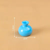 A small, bright blue resin vase with a round opening is shown against a beige background.