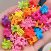 A collection of colorful plastic flower and star hair claw clips for kids displayed in a hand.