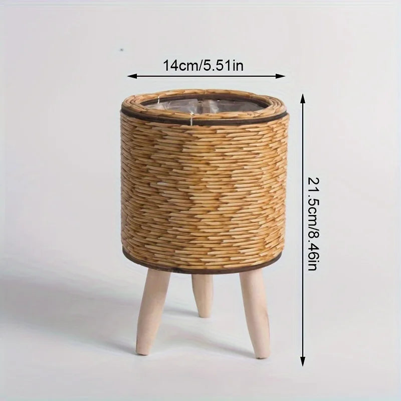 A rustic rattan planter with a round woven top and wooden legs, measuring 14cm in diameter.