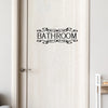 A white wooden door with a black decorative sign that reads BATHROOM.