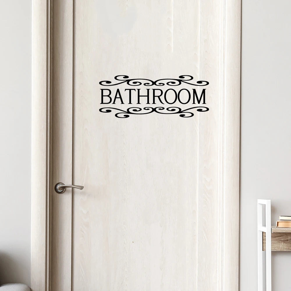 A white wooden door with a black decorative sign that reads BATHROOM.