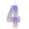 A sparkling purple number four candle decorated with a purple flower on a white base.