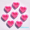 Pink heart shape acrylic charms arranged on a white background with shadows.