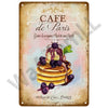 A vintage-style plaque for Cafe de Paris featuring a stack of pancakes with syrup and fruit.