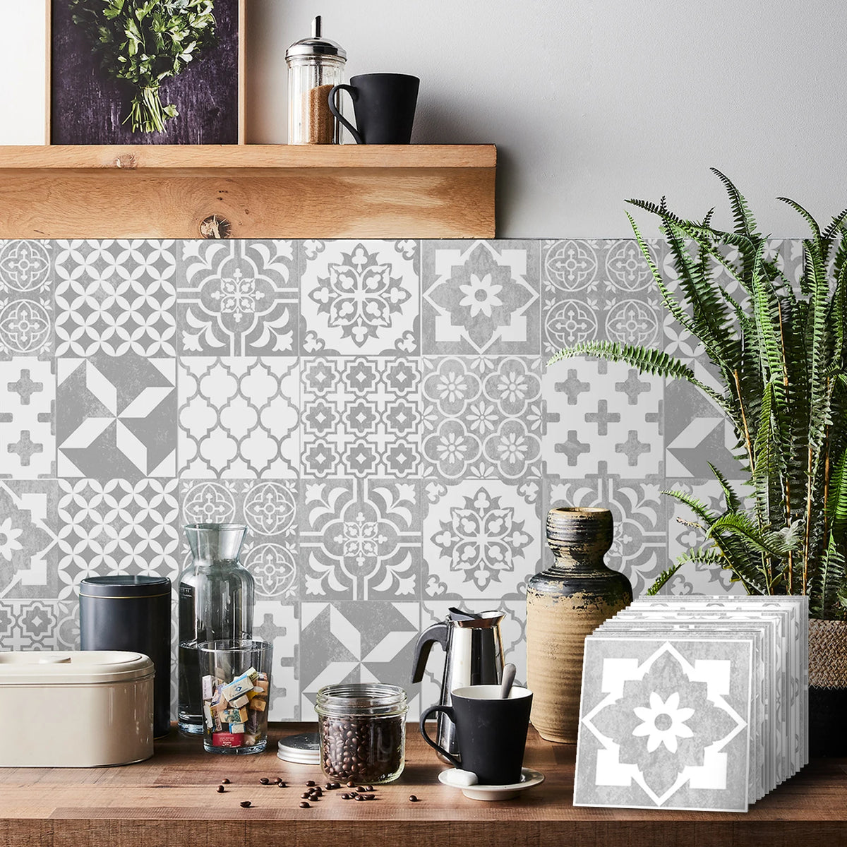 A rustic wooden surface displays self-adhesive tile wall stickers in gray and white geometric patterns with greenery.
