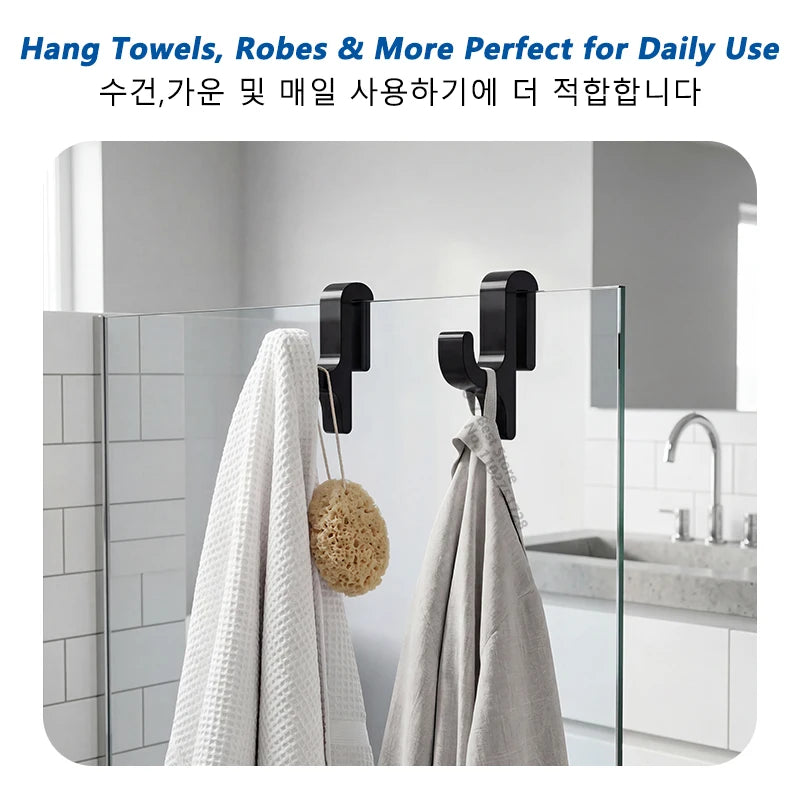 A set of black towel hooks hanging on a glass shower door, used for hanging towels and robes.