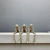 A set of realistic Halloween skeleton resin statues arranged in a seated position against a plain gray background.