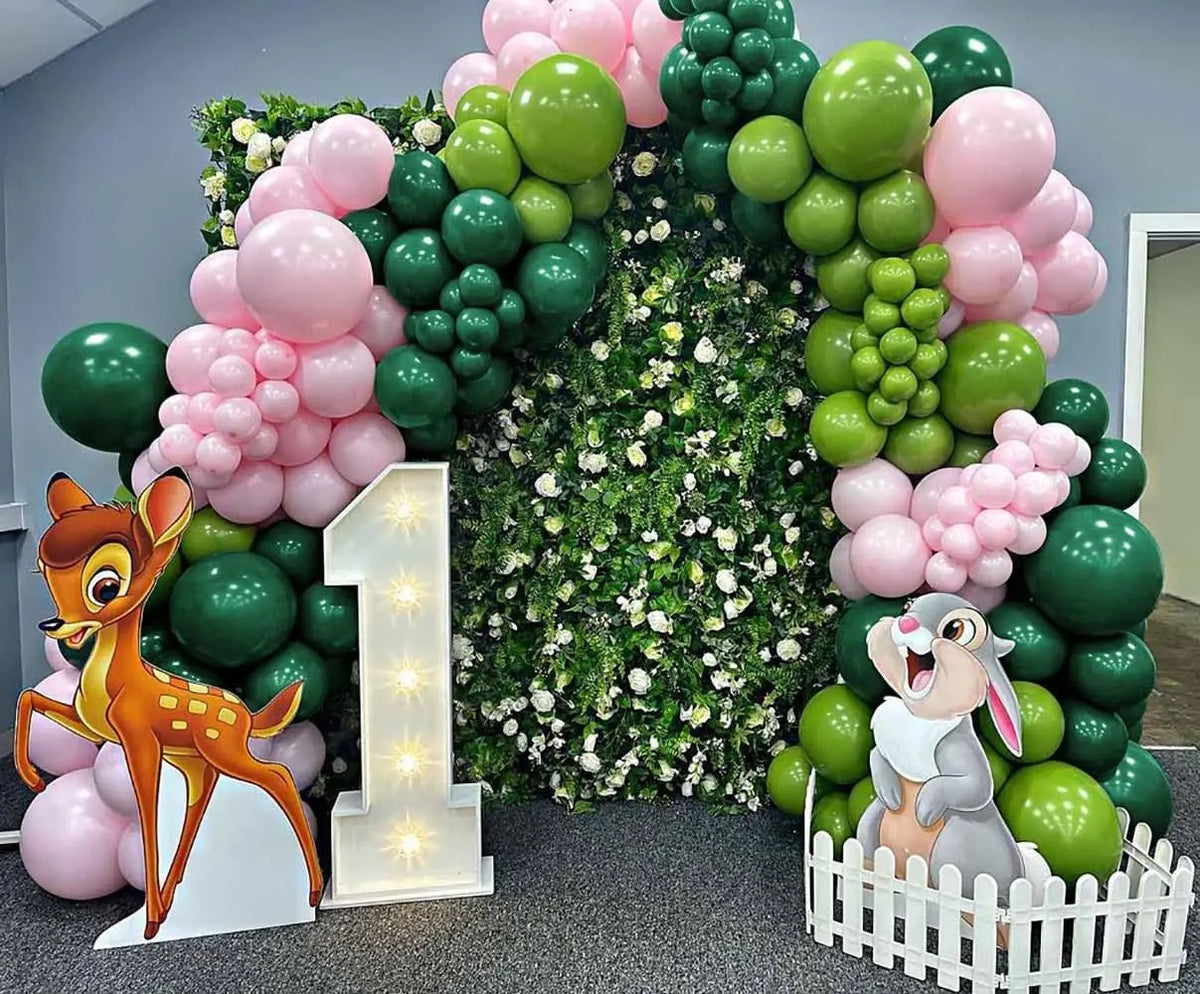 A balloon arch decoration featuring green and pink latex balloons with a deer figure and a rabbit figure.