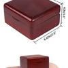 A square, dark reddish-brown music box with rounded edges shown resting on a person's hand.