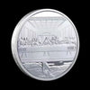 A silver commemorative coin depicting a scene from the Last Supper with figures seated at a table.
