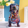 A colorful resin figurine of a dachshund dog in a sitting pose, displayed on a white box.