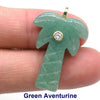 A polished green aventurine crystal shaped like a palm frond with a zircon charm, held by a person's finger.