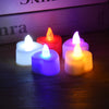 A collection of glowing LED heart-shaped tealight candles in white, red, purple, and orange on a dark wooden surface.
