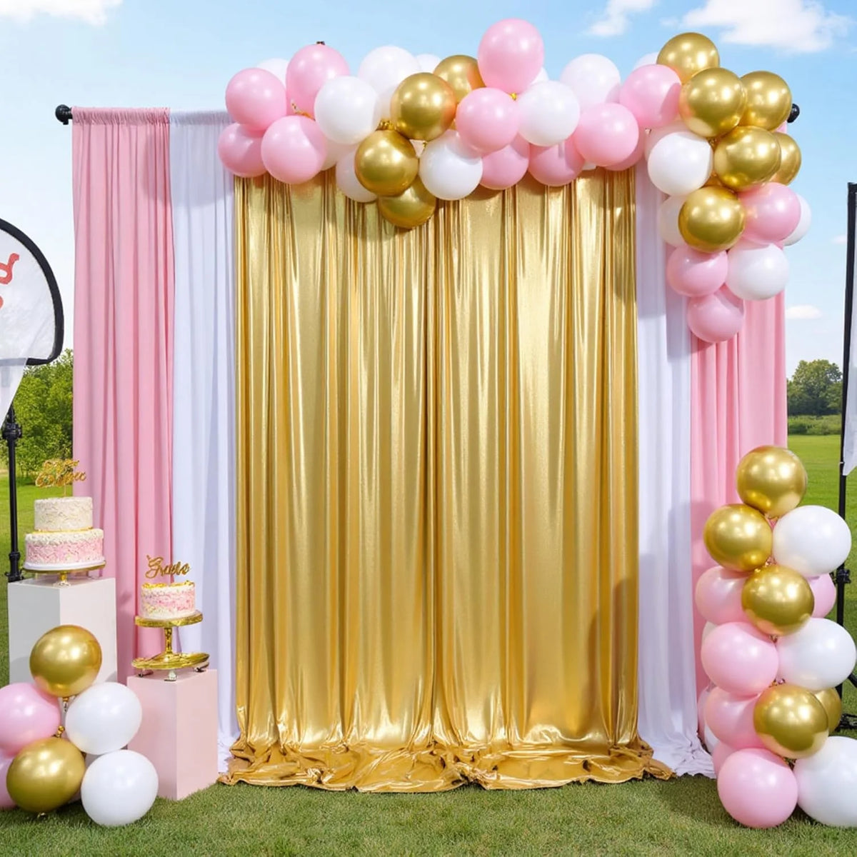 A gold and pink balloon backdrop curtain decorated with pink and white balloons and a tiered cake on a stand.