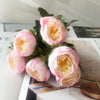 A bouquet of pink and peach silk rose and peony artificial flowers displayed on a white surface.