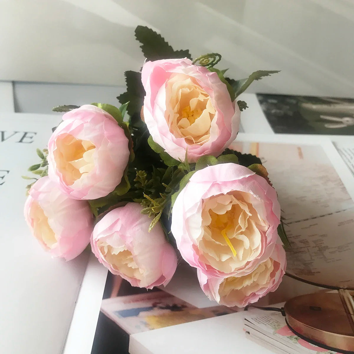 A bouquet of pink and peach silk rose and peony artificial flowers displayed on a white surface.