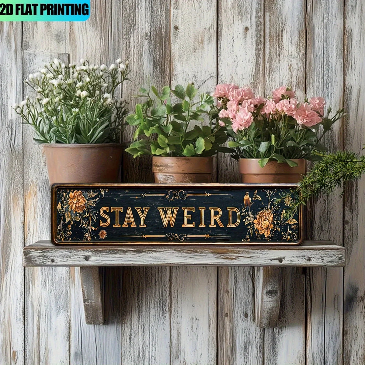 A wooden sign with the text STAY WEIRD surrounded by dried flowers and greenery on a rustic shelf.