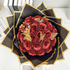 A bouquet of deep red glitter roses arranged in a dark wrapper with gold accents.