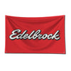 A red fabric flag featuring the white and gray Edelbrock logo, mounted for display.