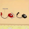 A red and black retro rotary desk phone miniature for dollhouse decor shown next to a ruler.