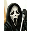 A person wearing a realistic Scream Ghost Face mask and black costume, holding a white prop.
