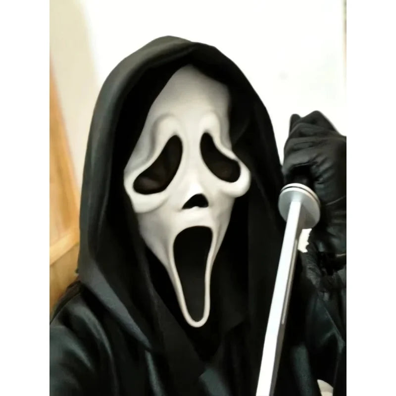 A person wearing a realistic Scream Ghost Face mask and black costume, holding a white prop.