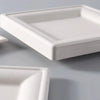 A white square paper plate is shown from a slight angle on a gray surface.