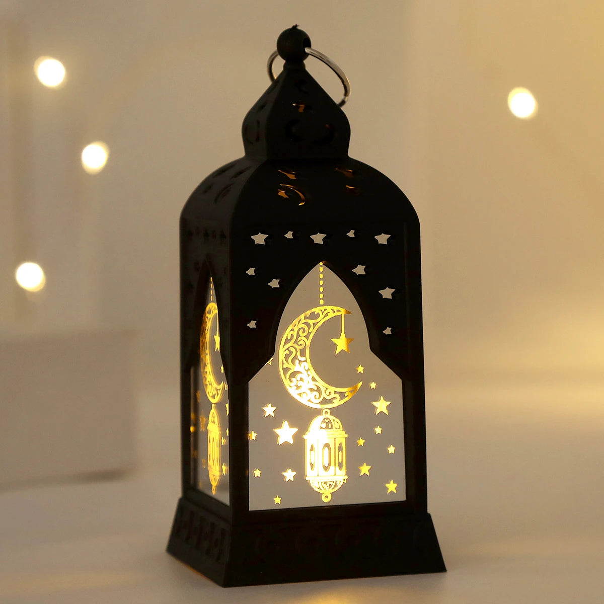 A black LED lantern featuring an intricate crescent moon and star design, illuminated with warm light.