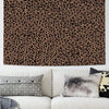A wall hanging featuring a brown and black leopard print tapestry above a white sofa with gray and black pillows.