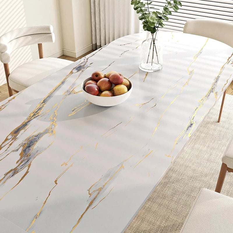 A white marble-patterned table top with gold veining, featuring a bowl of fruit and natural light.