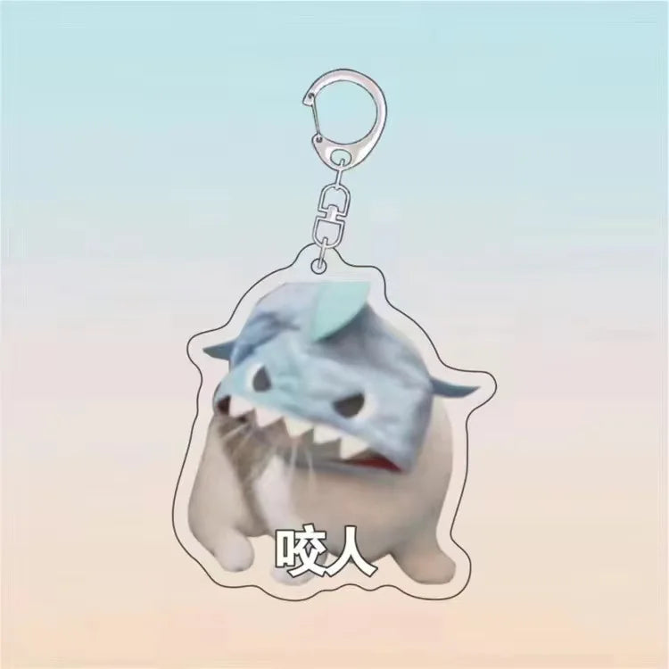 A light blue acrylic keychain shaped like a cat face with an open mouth and teeth, featuring Chinese characters.