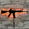 A black gun-shaped LED light fixture mounted on a stone wall, with a wire extending from the bottom.