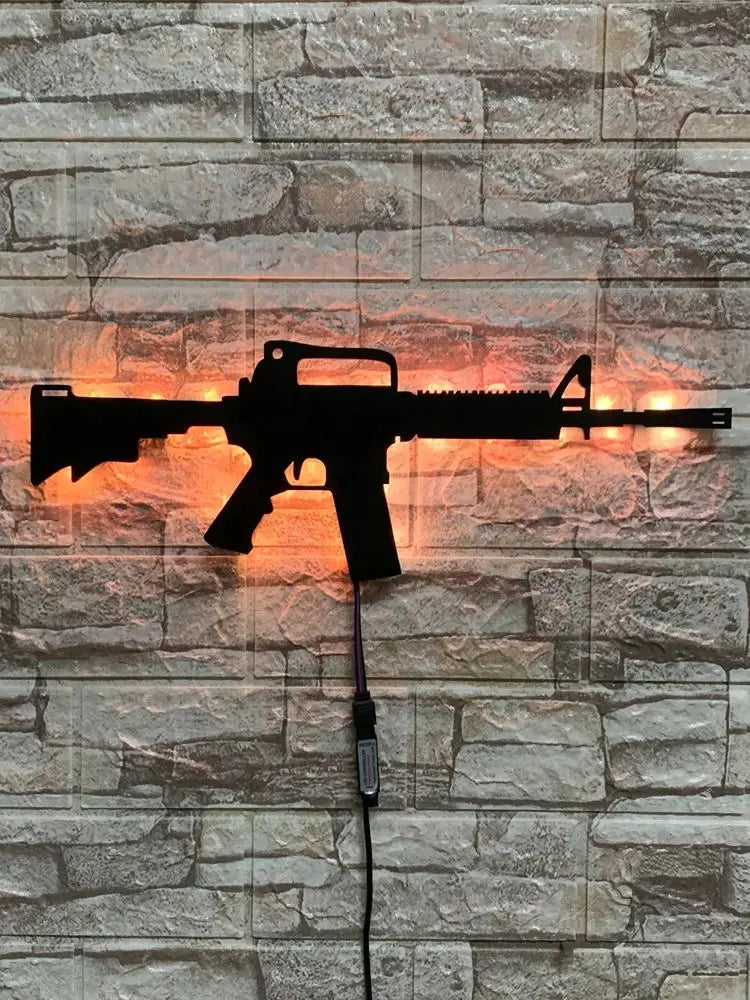 A black gun-shaped LED light fixture mounted on a stone wall, with a wire extending from the bottom.